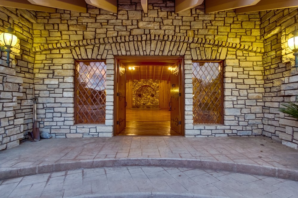 Stone archway and carved front doors of Alpine Castle at dusk